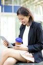 Young Asian female executive drinking coffee and using tablet PC