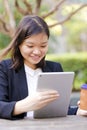 Young Asian female executive drinking coffee and using tablet PC