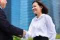 Young Asian female executive shaking hands with senior Asian businessman and smiling Royalty Free Stock Photo