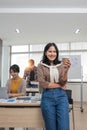 A focused young Asian female marketing assistant is working on her work on her laptop at her desk while her coworkers Royalty Free Stock Photo