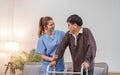 young asian female nurse care giver helping asian senior old man with mobility walker in living area of nursing home Royalty Free Stock Photo