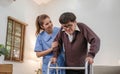 young asian female nurse care giver helping asian senior old man with mobility walker in living area of nursing home Royalty Free Stock Photo