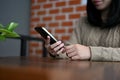 Young Asian female relaxing in the coffee shop, using her smartphone. cropped image Royalty Free Stock Photo