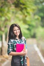 Young asian female student holding books while walking on the pa Royalty Free Stock Photo