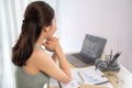 Young Asian female student watching teacher's live performance or video call on laptop in classroom at home Royalty Free Stock Photo