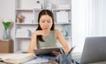 Young Asian female student watching teacher's live performance or video call on laptop in classroom at home Royalty Free Stock Photo