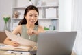 Young Asian female student watching teacher's live performance or video call on laptop in classroom at home Royalty Free Stock Photo