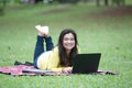 Young asian female university or college student lying on stomach in park