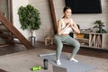 Young asian fitness girl doing squats workout at home, follow online sport gym instructor, standing on floor mat and Royalty Free Stock Photo