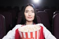 young asian girl with big basket of popcorn watching movie Royalty Free Stock Photo