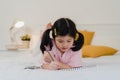 Young Asian girl drawing at home. Asia japanese woman child kid relax rest fun happy draw cartoon in sketchbook before sleep lying