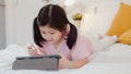 Young Asian girl drawing at home. Asia japanese woman child kid relax rest fun happy using tablet draw cartoon before sleep lying Royalty Free Stock Photo