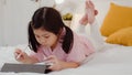 Young Asian girl drawing at home. Asia japanese woman child kid relax rest fun happy using tablet draw cartoon before sleep lying Royalty Free Stock Photo