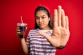 Young asian girl drinking cola fizzy refreshment using straw over isolated red background with open hand doing stop sign with Royalty Free Stock Photo