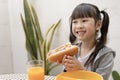 Young Asian girl eating breakfast and orange juice on the table at home still happy Royalty Free Stock Photo