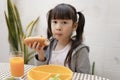 Young Asian girl eating breakfast and orange juice on the table at home still happy. Royalty Free Stock Photo