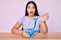 Young asian girl eating measure meter doing diet for weight loss afraid and shocked with surprise and amazed expression, fear and Royalty Free Stock Photo