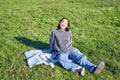 Young asian girl enjoying sunny day outdoors. Happy student having picnic on grass in park, playing ukulele Royalty Free Stock Photo