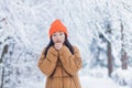 Young asian girl freezes in the park waiting for a date, on a winter snowy day, a woman warmly dressed