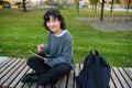 Young asian girl with graphic pencil and tablet, sits in park on bench, draws scatches, does her homework outdoors Royalty Free Stock Photo