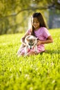 Young Asian girl holding puppy sitting on grass Royalty Free Stock Photo