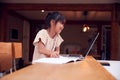 Young Asian Girl Home Schooling Working At Table Using Laptop