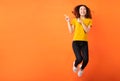 Young asian girl jumping up on orange background Royalty Free Stock Photo