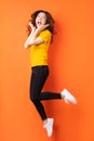 Young asian girl jumping up on orange background Royalty Free Stock Photo