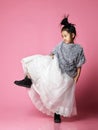 Young asian girl kid in long white skirt, grey fluffy sweater and black boots step on vigorously Royalty Free Stock Photo