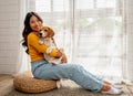 Young Asian girl look at camera with smiling also hold and hug beagle dog and sit in front of glass door in her house and she look Royalty Free Stock Photo