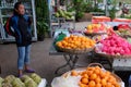 A young Asian girl sells fruit on a city street