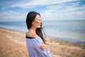Young asian girl is standing on the beach, looking away and thinking
