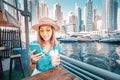 Young Asian girl texting on her phone and reading news on social networks in the beautiful Marina port in Dubai Royalty Free Stock Photo