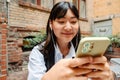 Young asian girl using mobile phone while sitting in cafe outdoors Royalty Free Stock Photo