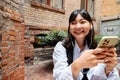 Young asian girl using mobile phone while sitting in cafe outdoors Royalty Free Stock Photo