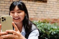 Young asian girl using mobile phone while sitting in cafe outdoors Royalty Free Stock Photo