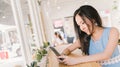 Young Asian girl using smartphone in modern coffee shop or bakery cafe. Mobile phone application technology concept Royalty Free Stock Photo