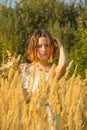 A young asian girl in a white dress walking in a field with fluffy ears. A model from back with a short haircut and wildflowers. Royalty Free Stock Photo