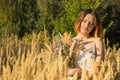 A young Asian girl in a white dress walking on a field with fluffy ears.  A model with a short haircut and a wildflowers bouquet Royalty Free Stock Photo