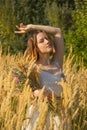 A young Asian girl in a white dress walking in a field with fluffy ears. A model with a short haircut and a wildflowers bouquet. Royalty Free Stock Photo