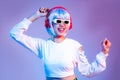 Young asian girl in white fashion sweatshirt wearing sunglasses and headphone dancing on the purple screen background Royalty Free Stock Photo