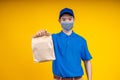 Young Asian handsome delivery man wearing mark holding a food paper bag