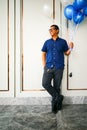 A young Asian handsome man in casual blue shirt was smiling while holding a balloon