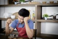 Young Asian handsome man feels stressed and bored, touched head while eating, having breakfast meal on wooden table in kitchen Royalty Free Stock Photo