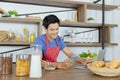 Young Asian handsome man is having, eating cereals and cornflakes in breakfast meal while using smart phone and laptop for working Royalty Free Stock Photo