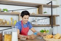 Young Asian handsome man is having, eating cereals and cornflakes in breakfast meal while using smart phone and laptop for working Royalty Free Stock Photo