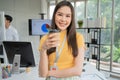 Young Asian Happy Businesswoman or intern holding coffice cup in Modern Office background is Colleagues discuss with new startup Royalty Free Stock Photo