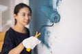 Young asian happy woman painting interior wall