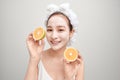 Young Asian having white facial clay mask and holding orange piece