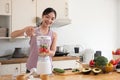 Young Asian healthy beautiful woman with casual clothes is smile putting cucumber, banana and tomato fruit in blender Royalty Free Stock Photo